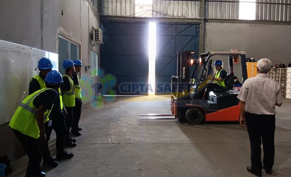 Operator forklift berlisensi K3 mengoperasikan forklift dengan aman di lingkungan industri