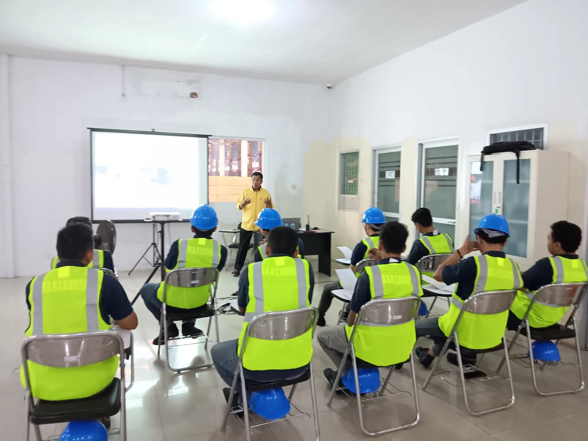 Inspektor K3 mengevaluasi program keselamatan bersama supervisor di pabrik Sidoarjo.