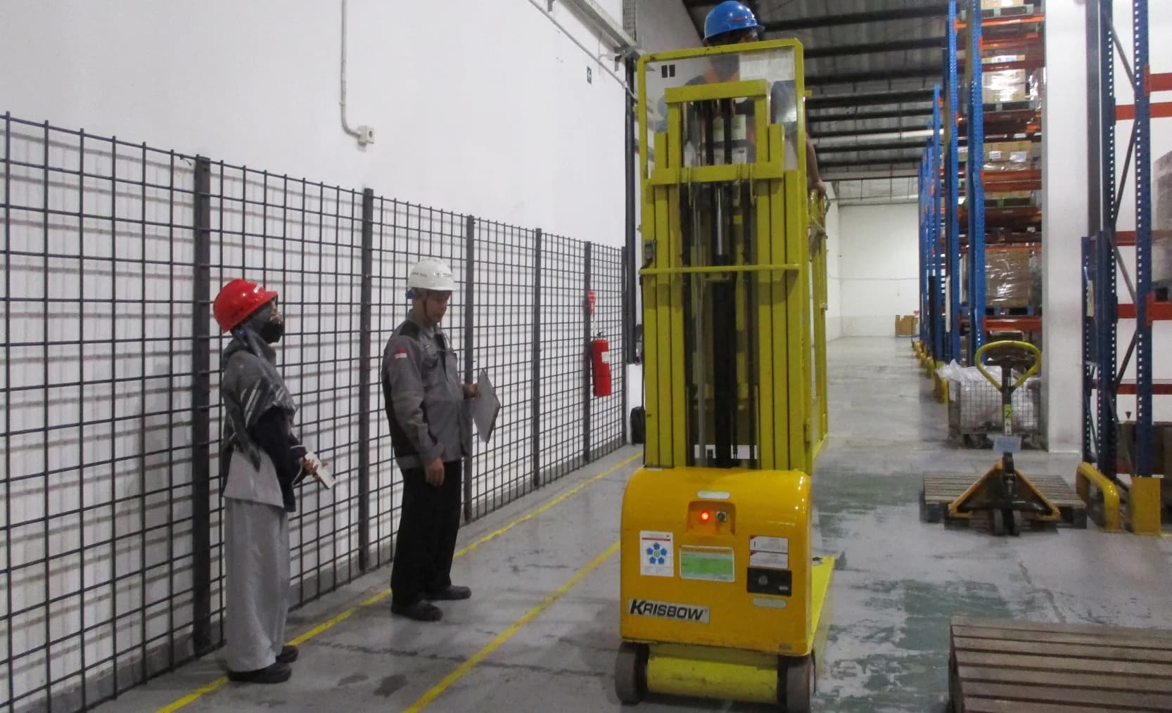 Petugas K3 berseragam inspector hijau melakukan pemeriksaan awal forklift dan crane di area pabrik sebagai bagian dari persiapan Riksa Uji K3.